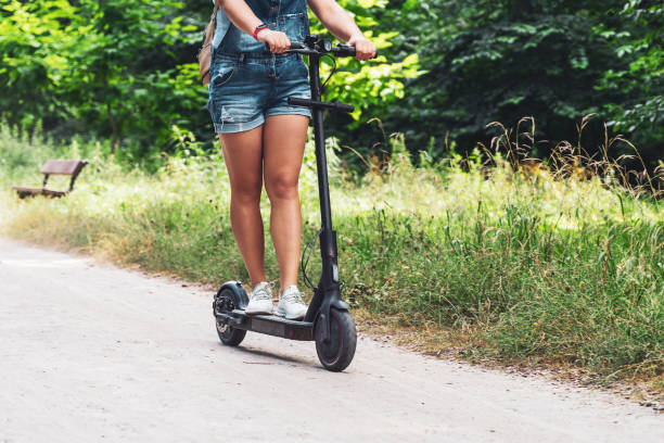 Female feet on an electric scooter riding on a dirt road stock photo