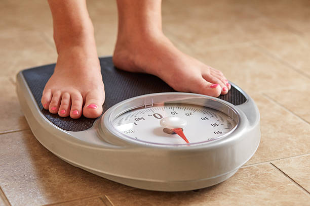 Female feet on weight scale A pair of female feet on a bathroom scale weight scale stock pictures, royalty-free photos & images
