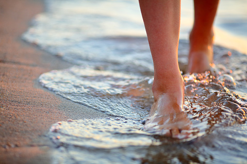 Female feet step on the sea wave. Summer vacations concept