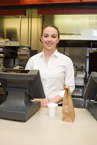 Female food service worker at counter with a coffee and bag stock photo