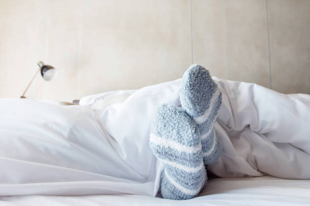 mujer pies en calcetines de lana de raya caliente - posturas para dormir  fotografías e imágenes de stock
