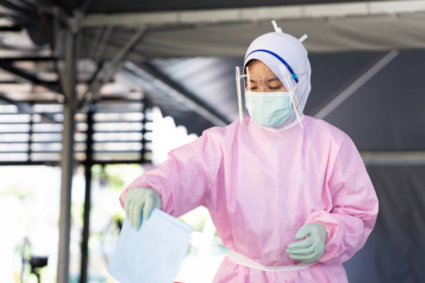 Female frontliner in Malaysia performing her tasks during the coronavirus pandemic while wearing full PPE stock photo