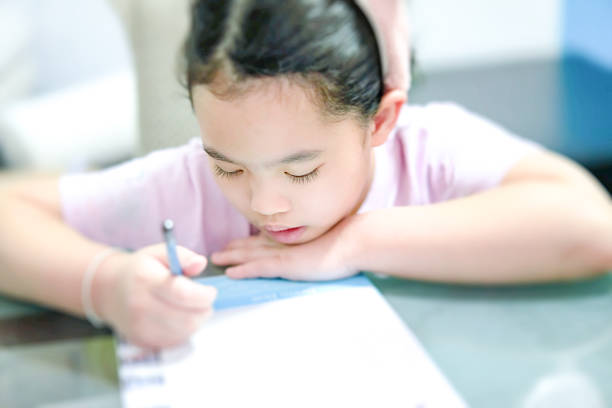 female girl is writing on table while learning at home stock photo