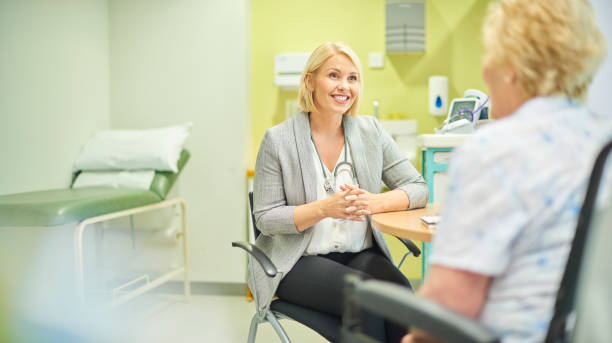 female gp listening to patient a female doc talks to a senior patient in the clinic general practitioner stock pictures, royalty-free photos & images