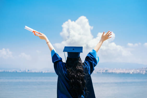 Female graduate student with arms raised stock photo