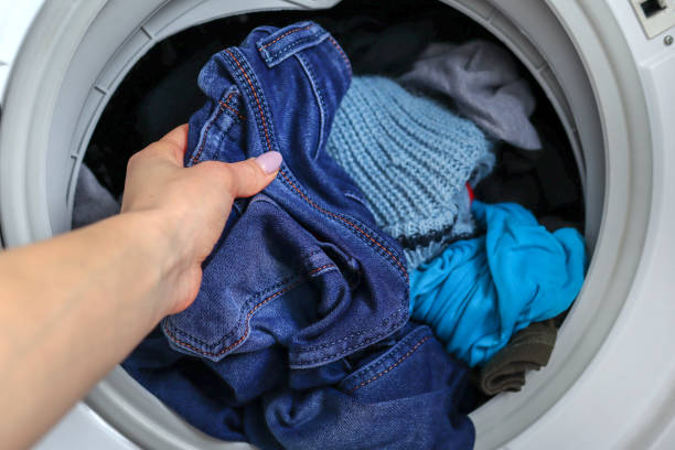 Female hand getting out clean jeans from washing machine stock photo