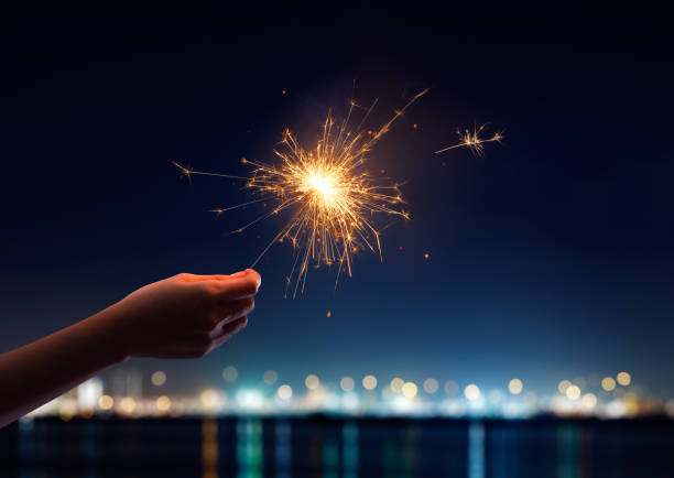 Female hand holding a burning sparkler Female hand holding a burning sparkler sparkler firework stock pictures, royalty-free photos & images