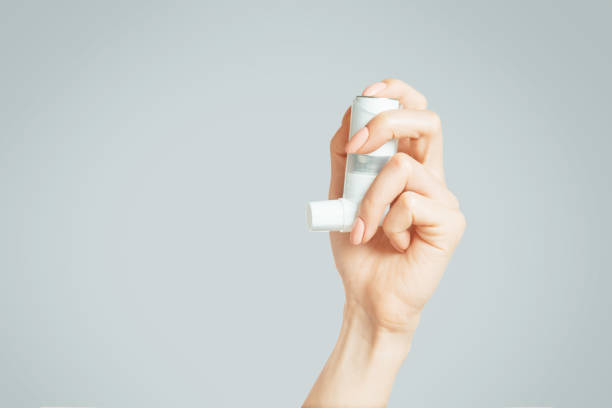 Female hand holding a medical asthma inhaler. stock photo