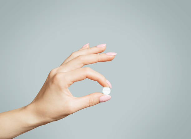 Female hand holding a round white pill or vitamin. stock photo