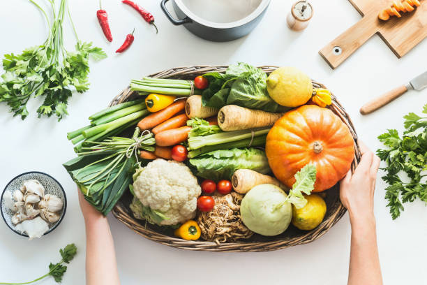 Female hand holding big tray with various colorful organic farm harvest vegetables stock photo