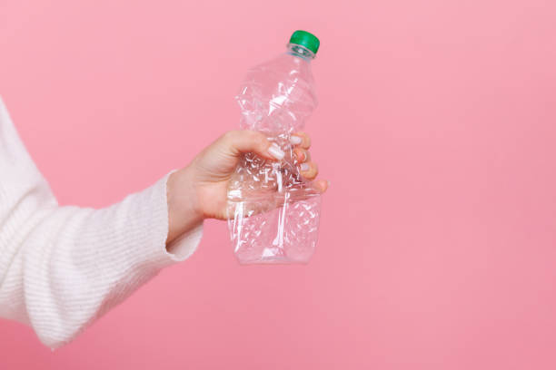 Female hand holding plastic bottle with green cap, sorting her rubbish, worrying about environment. stock photo