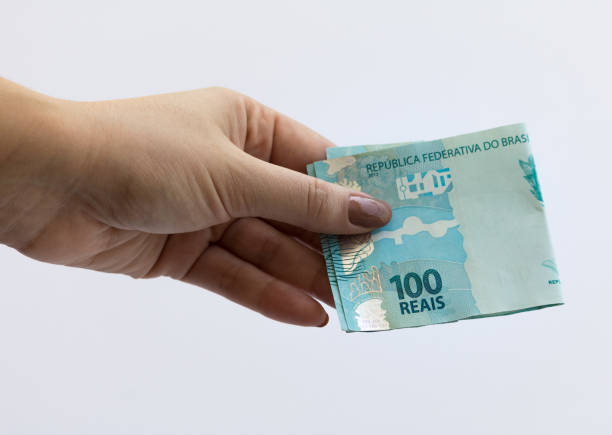 Female hand holding Real hundred note. Brazilian money. Selective focus. Brazilian currency. Economy, inflation, business. 100. stock photo