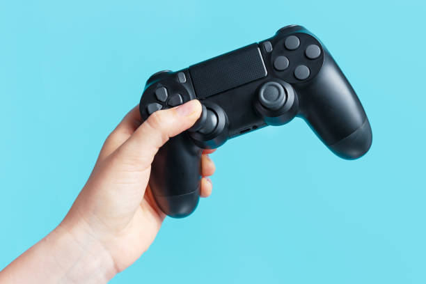 Female hand holding video game joystick on blue background. stock photo