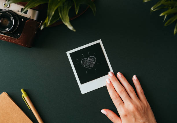 Female hand holds a polaroid picture with a heart stock photo