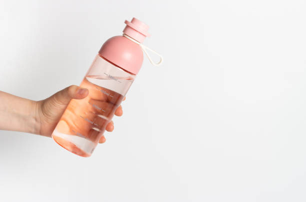 A female hand holds water bottle on white background, copy space A female hand holds water bottle on a white background, copy space reusable water bottle stock pictures, royalty-free photos & images