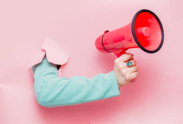 Female hand in classic blue jacket with megaphone Female hand in classic blue jacket with megaphone looks out from pink background audio electronics stock pictures, royalty-free photos & images