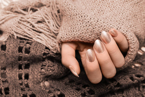 Female hand with silver nail design. Silver nail polish manicured hand. Woman hands hold brown wool shawl. stock photo