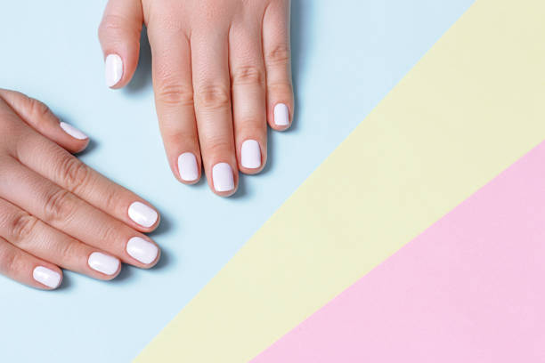Female hand with white manicure on a on pastel colored background with copy space, top view Female hand with white manicure on a on pastel colored background with copy space, top view gel nail polish stock pictures, royalty-free photos & images