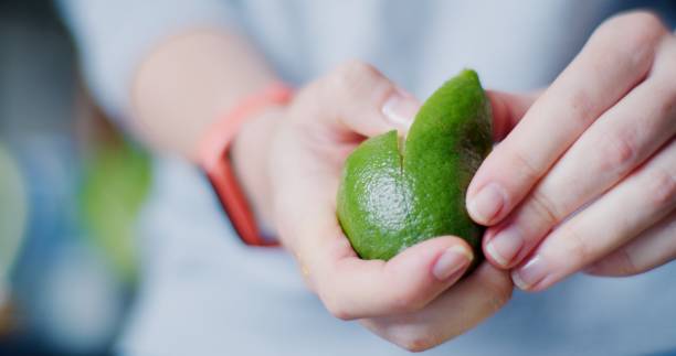 Female hands are peeling a lime to use the peel for food stock photo