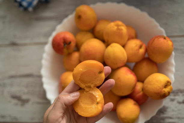 female hands cutting fresh sweet peaches to make peach jam. - mitrovic stockfoto's en -beelden