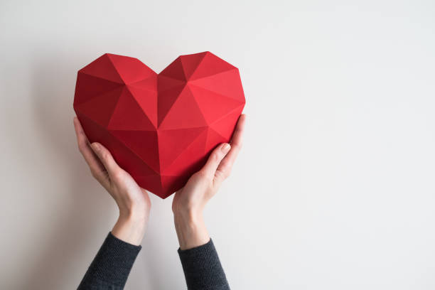 female hands holding red polygonal heart shape - fond imagens e fotografias de stock