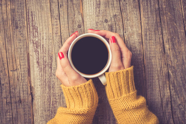 weibliche hände in warmen pullover hält tasse kaffee - hand holding coffee stock-fotos und bilder