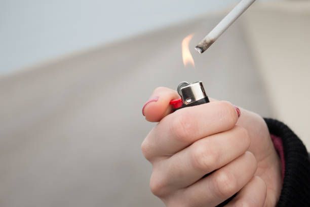 female hands lighting a cigarette close-up on lighter and fire. stock photo