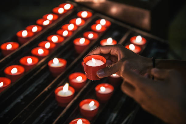 female hands lighting candle in church - fire portugal imagens e fotografias de stock