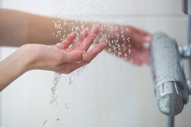 le mani femminili provano la temperatura dell'acqua sotto la doccia - doccia foto e immagini stock