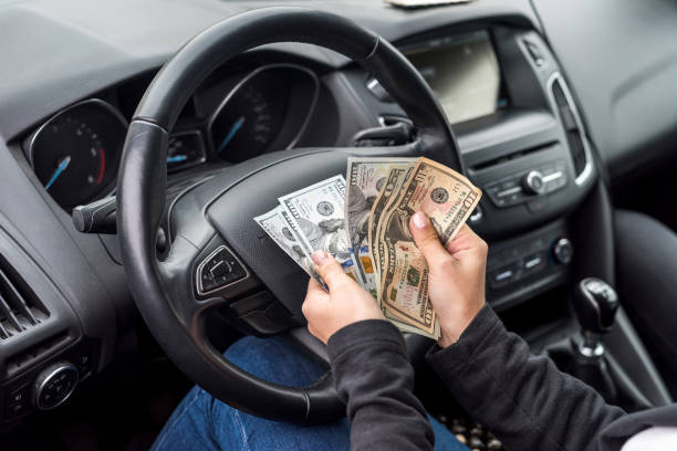 Female hands with dollar banknotes closeup on steering wheel stock photo
