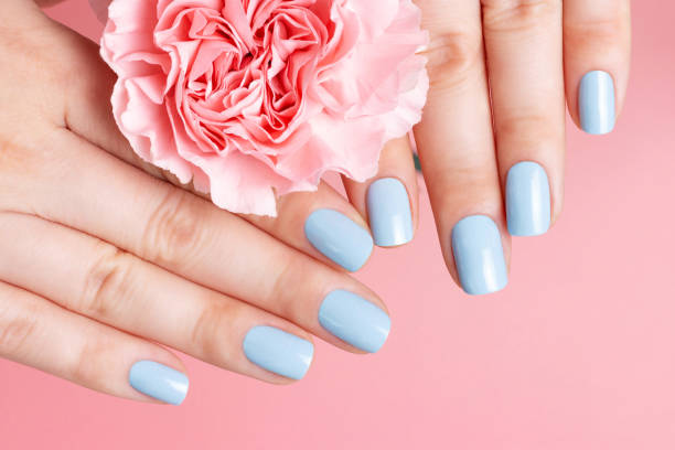 Female hands with manicure on flower on pink background, top view stock photo