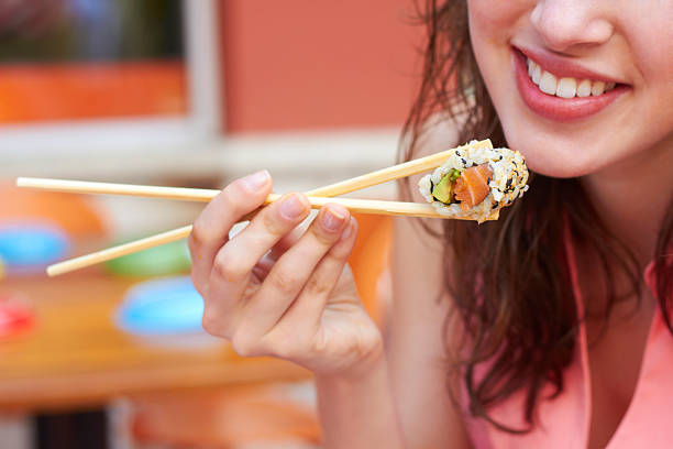 Female happily eating sushi with chopsticks  stock photo
