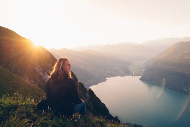 Female hiker relaxes on mountain ridge at sunrise stock photo