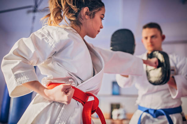 Female karate player practicing with trainer Young female karate player with trainer using focus mitts during training karate stock pictures, royalty-free photos & images