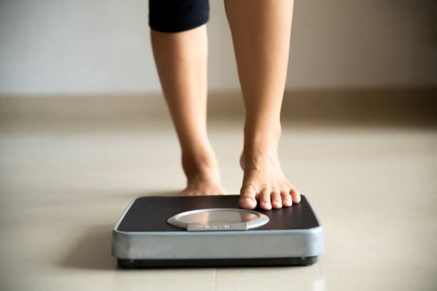 Female leg stepping on weigh scales. Healthy lifestyle, food and sport concept. stock photo