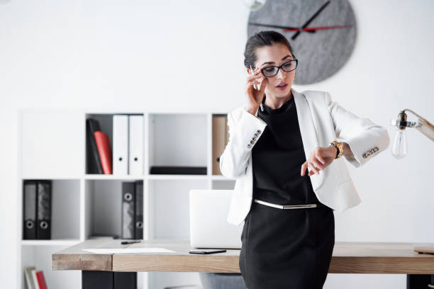 een vrouwelijke manager controleren haar horloge. communiceren over, tijd, business, termijnen, snelle leveringen, snelle klantenservice, eenvoudige oplossingen, tijdwinst. - woman horloge stockfoto's en -beelden