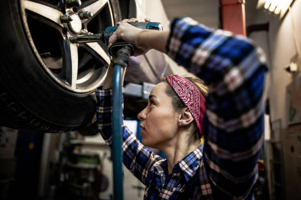 femme mécanicien travaillant sur le service de pneus voiture - femme tire photos et images de collection