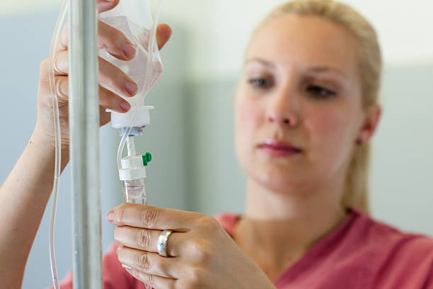 female medical assistant prepares an infusion - focus on foreground stock photo