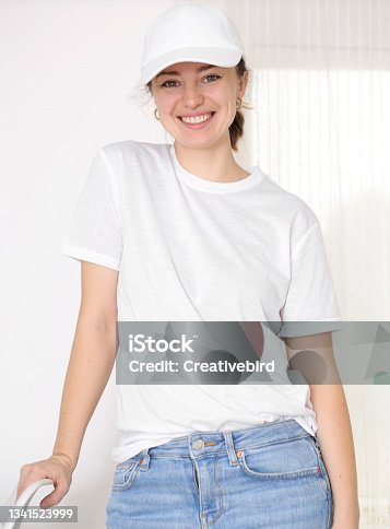 istock Female model wearing a white t-shirt and baseball cap. White cap and t-shirt mockup, template for picture, text or logo. Smiling attractive girl. Free space, copy space. 1341523999