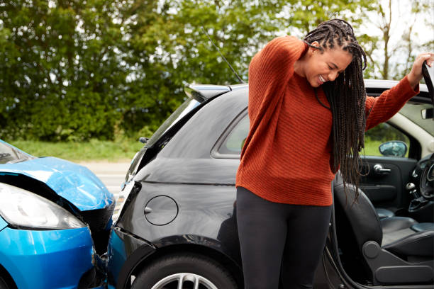 vrouwelijke automobilist met whiplash letsel in auto-ongeluk uit het voertuig - fixing car pain stockfoto's en -beelden