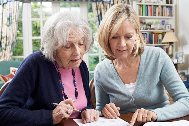 Female Neighbor Helping Senior Woman To Complete Form stock photo