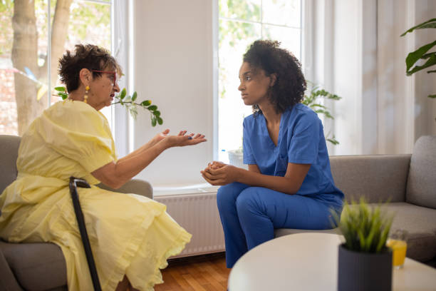 Female nurse and senior woman talking in retirement home stock photo