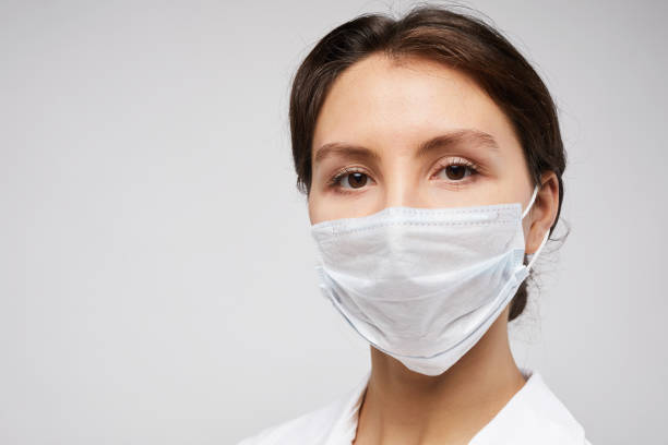 Female Nurse Closeup Portrait Head and shoulders portrait of female doctor wearing protective mask and looking at camera posing against white background, copy space nurse face stock pictures, royalty-free photos & images