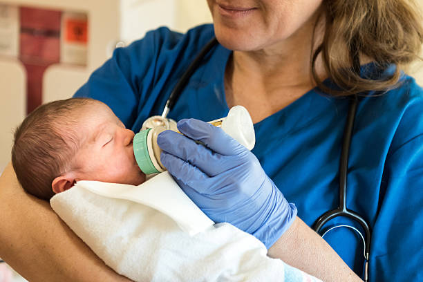 신생아에게 먹이를 주는 여성 간호사 - baby formula 뉴스 사진 이미지
