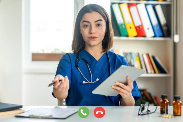 Female nurse talking on video call Female nurse talking on video call nurse talking to camera stock pictures, royalty-free photos & images