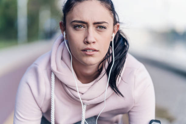 Female on the start position for running Close-up image of young female getting ready for running, looking ahead and listening to music Portable DVD Player stock pictures, royalty-free photos & images