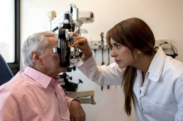 Female optometrist using a phoropter on senior patient Female optometrist using a phoropter on senior patient at an eye clinic eye doctor stock pictures, royalty-free photos & images