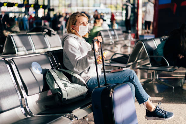 A female passenger in a medical mask is waiting for a flight at the airport. stock photo
