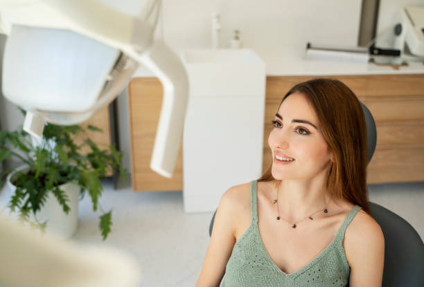 Female patient looking in the mirror and checking up teeth after treatment stock photo