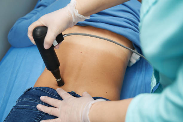 Female patient receiving extracorporeal shockwave therapy in clinic stock photo